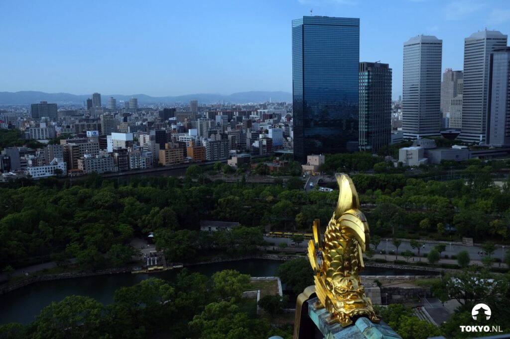Panoramablick auf Osaka-Skyline mit goldener Dachverzierung der Osaka-Burg im Vordergrund und modernen Wolkenkratzern im Hintergrund