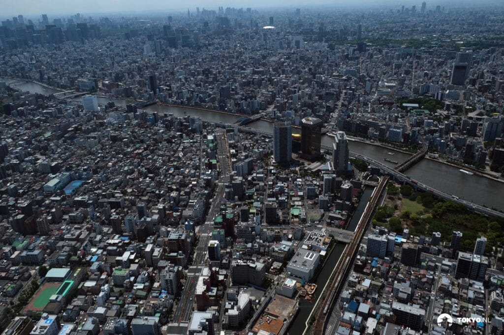Luftaufnahme von Tokyo vom Skytree aus - Panoramablick über die dicht bebaute Metropole mit dem Sumida-Fluss, der sich durch die Stadt schlängelt, und Wolkenkratzern am Horizont.