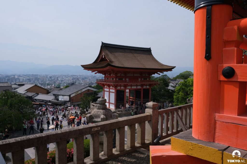 Traditionelle rote Tempelarchitektur des Kiyomizu-dera mit Holzgeländer und Blick über Kyoto während des Tages mit vielen Besuchern