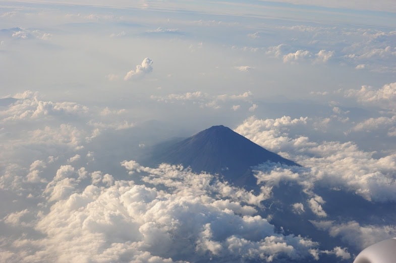 Mount Fuji ragt majestätisch über einer Wolkendecke empor, aufgenommen aus der Vogelperspektive mit dramatischen Wolkenformationen
