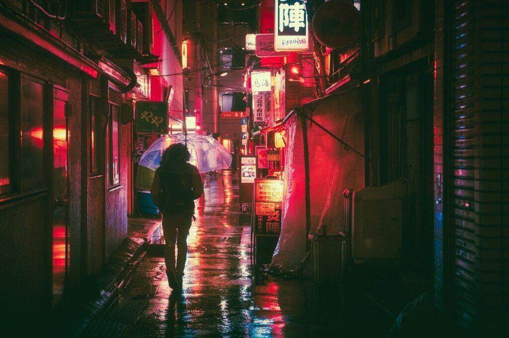 Spaziergänger im Dunkeln in Japanischer Straße bei Regen