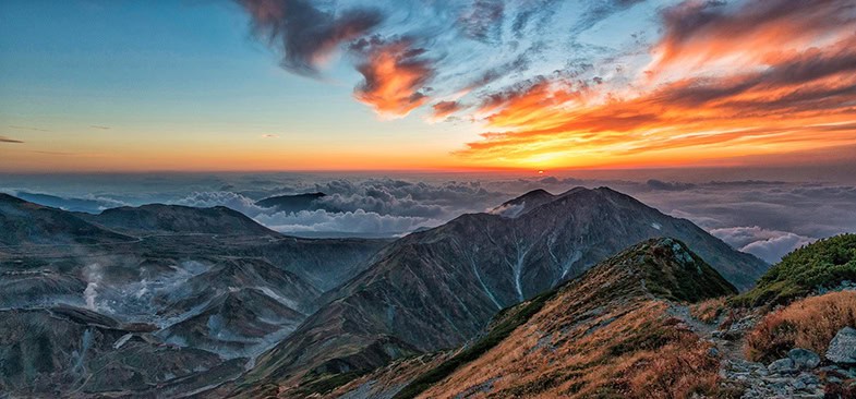 Spektakulärer Sonnenuntergang über einer japanischen Berglandschaft mit leuchtend orangefarbenem Himmel und Wolkenmeer