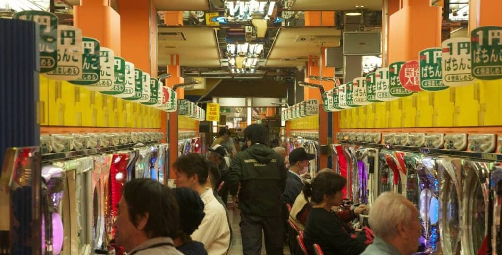 Innere einer Pachinko-Halle mit Reihen von Pachinko-Automaten und Spielern in den typisch engen, lauten Spielgängen