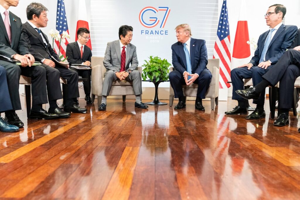 G7-Gipfeltreffen mit japanischen und amerikanischen Delegationen, erkennbar an den Flaggen und dem offiziellen G7 France-Logo im Hintergrund