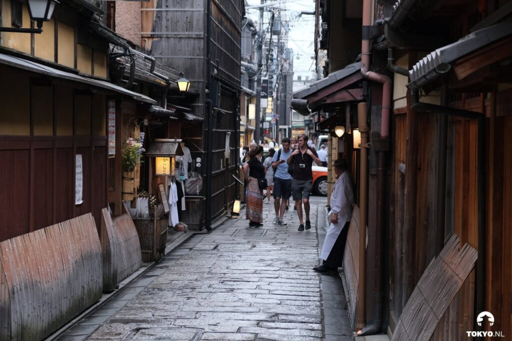 Authentische Kopfsteinpflaster-Gasse in Gion mit traditionellen Holzhäusern und Touristen