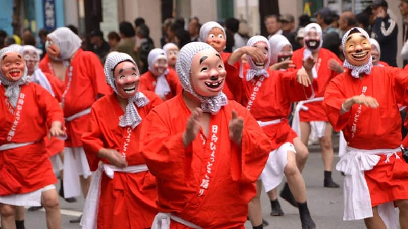 Festivalgruppe in roten Gewändern und weißen Masken beim Hakata-Festival