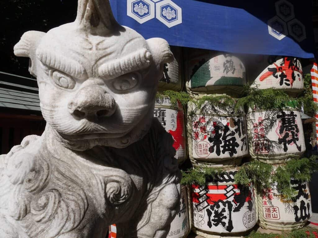 Steinlöwe-Statue vor Sake-Fässern mit japanischen Schriftzeichen