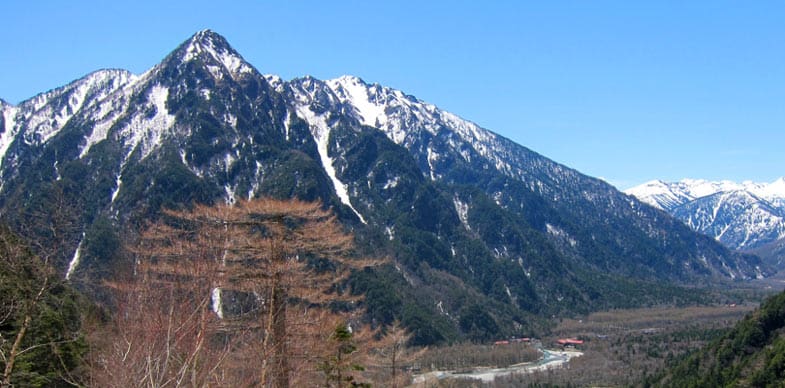 Schneebedeckte Gipfel der japanischen Alpen unter strahlend blauem Himmel mit einem trockenen Tal im Vordergrund