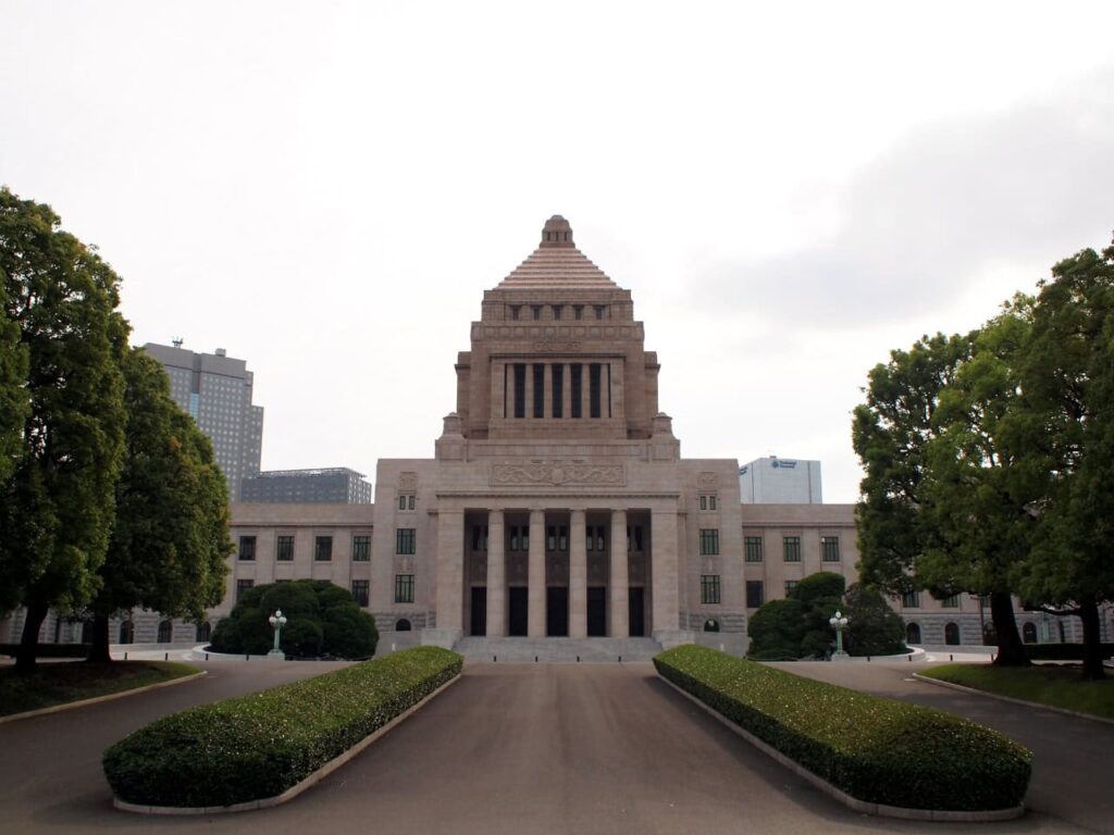 Das japanische Parlamentsgebäude (Kokkai-gijidō) in Tokio mit seiner charakteristischen Pyramidenstruktur, umgeben von gepflegten Grünanlagen und symmetrischen Gehwegen.