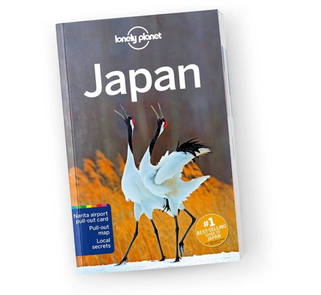 "Lonely Planet Japan" Reiseführer mit charakteristischem Cover zweier tanzender weißer Kraniche vor goldenem Herbstlaub, Symbol für Japan
