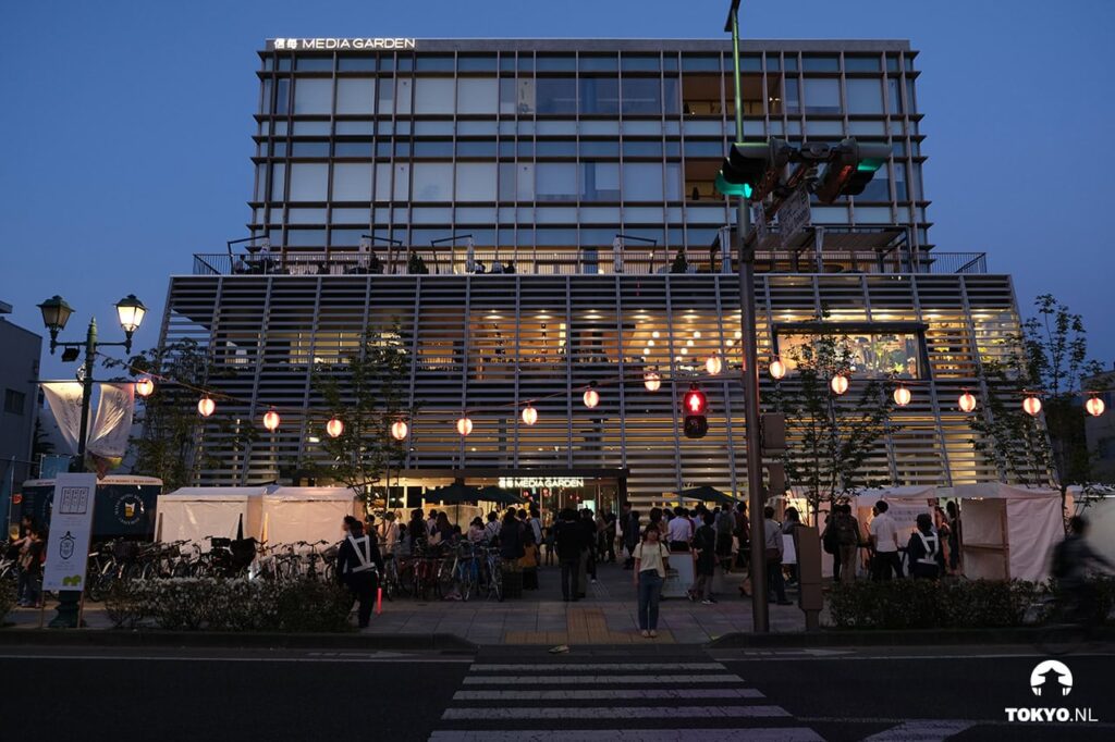 Abendliches Straßenfest vor dem beleuchteten Media Garden Gebäude in Matsumoto