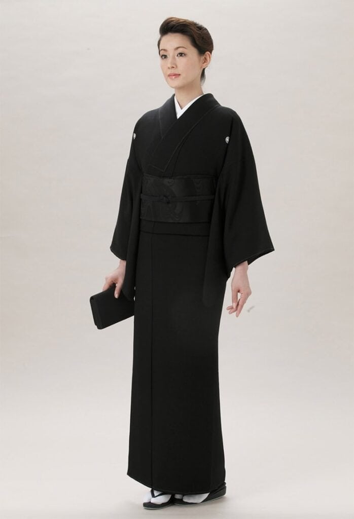 Eine Frau in einem schwarzen Mofuku-Kimono, dem formellen schwarzen Trauergewand, das zu feierlichen und traurigen Anlässen getragen wird.