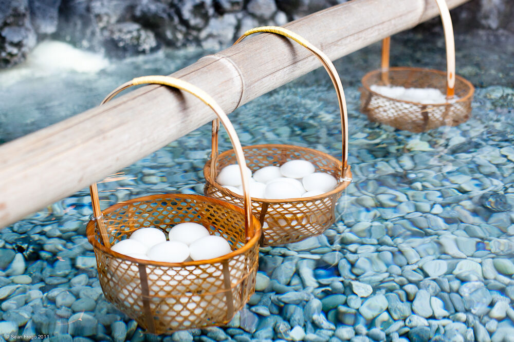 Traditionelle Onsen-Eier in Bambus-Körben zum Kochen in heißen Quellen mit Vulkansteinen und authentischem japanischem Kochverfahren