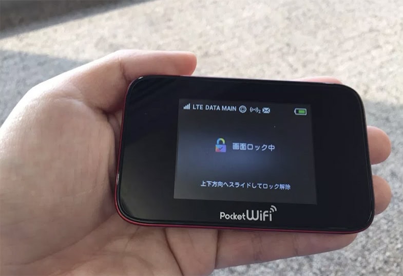 Hand hält ein japanisches Pocket WLAN Gerät für mobiles Internet mit LTE-Anzeige auf dem Bildschirm