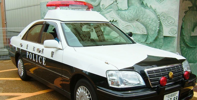 Schwarz-weißes japanisches Polizeiauto mit roten Signalleuchten auf einem Parkplatz