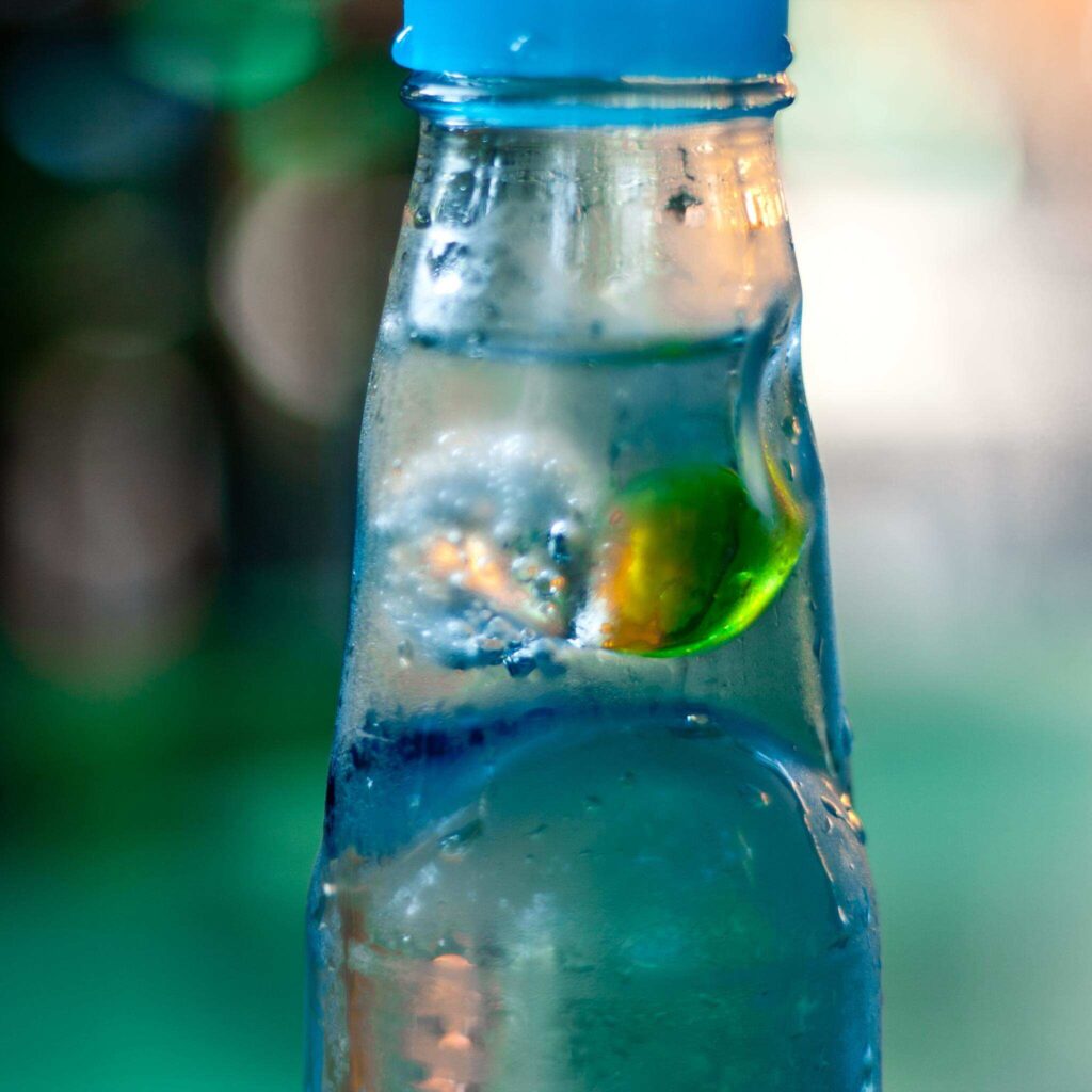 Traditionelle japanische Ramune-Limonade in Glasflasche mit Glaskugelverschluss und grüner Limette als erfrischendes Onsen-Getränk
