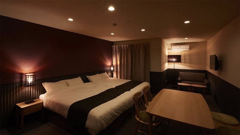Elegantes Hotelzimmer mit Doppelbett, warmer Beleuchtung und modernem Design in erdigen Brauntönen
