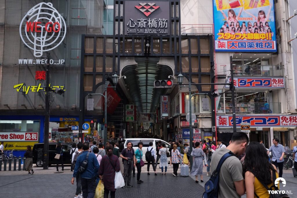 Eingang zur überdachten Shinsaibashi-Einkaufsstraße in Osaka mit traditioneller Architektur und vielen Geschäften