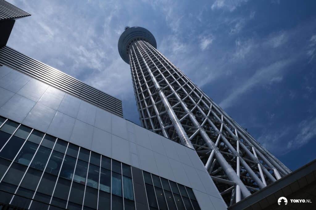 Tokyo Skytree von unten fotografiert - Dramatische Froschperspektive des modernen Sendeturms mit seiner charakteristischen Stahlgitterstruktur vor blauem Himmel