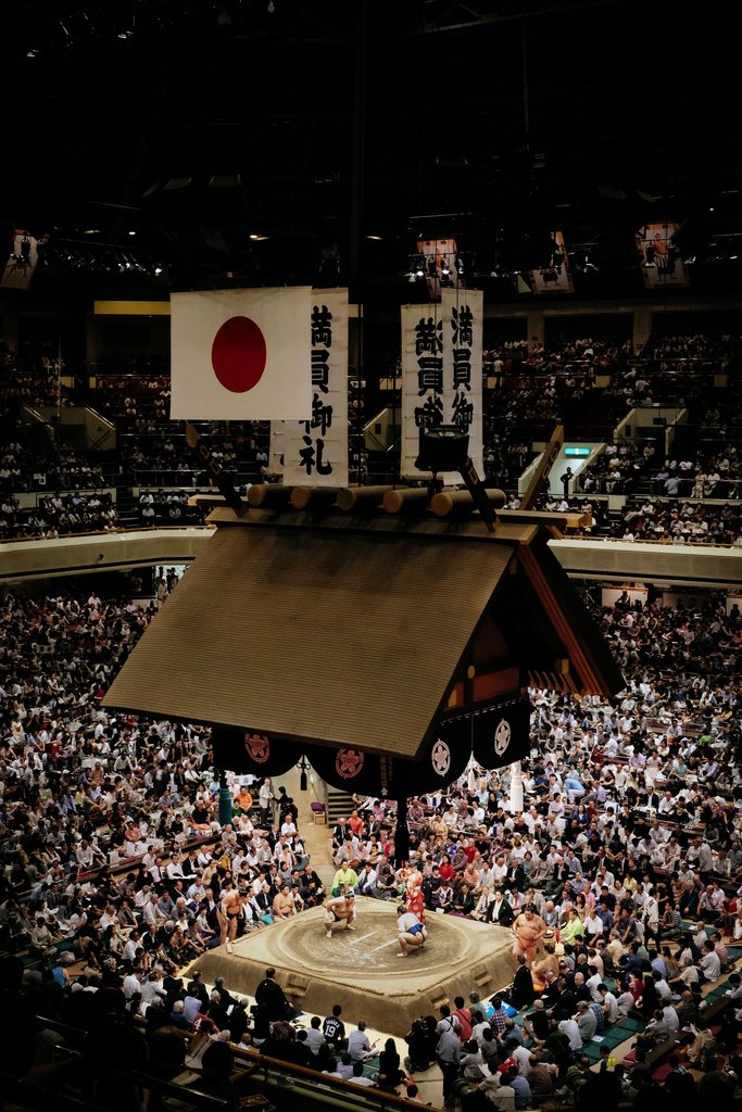 Das Innere des Kokugikan Stadiums während eines Sumo-Turniers mit dem heiligen Dohyo-Ring und tausenden begeisterten Zuschauern