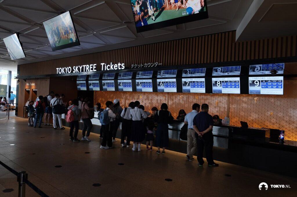 Ticketschalter im Tokyo Skytree - Moderner Ticketbereich mit mehreren Automaten und wartenden Besuchern, deutlich sichtbar die Beschriftung "TOKYO SKYTREE Tickets".