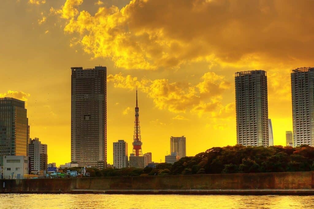 Tokyo Tower ragt zwischen Wolkenkratzern hervor bei goldenem Sonnenuntergang mit dramatischen Wolken