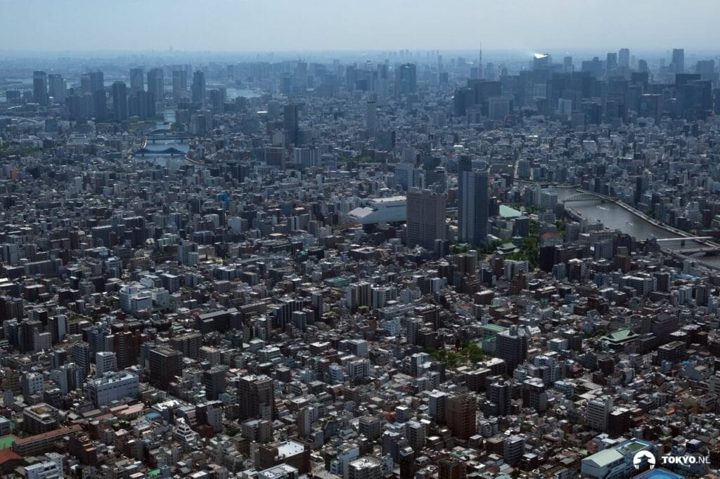Vogelperspektive auf Tokyo - Luftaufnahme der dicht besiedelten Metropole mit unzähligen Gebäuden, die sich bis zum Horizont erstrecken.
