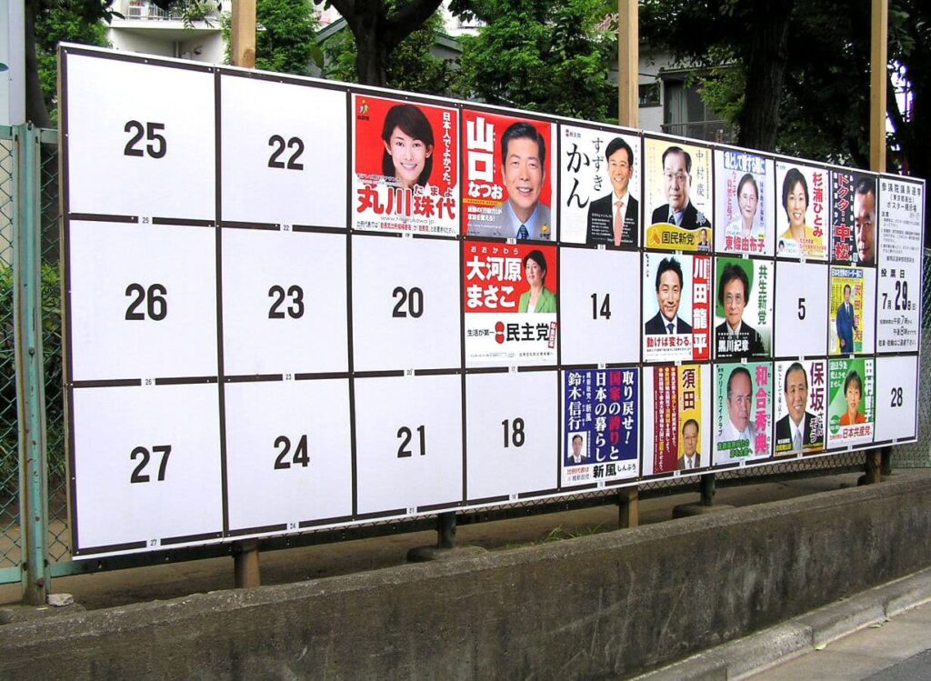 Offizielle Wahlplakatwand in Japan mit nummerierten Feldern und farbigen Porträts der Kandidat:innen verschiedener Parteien