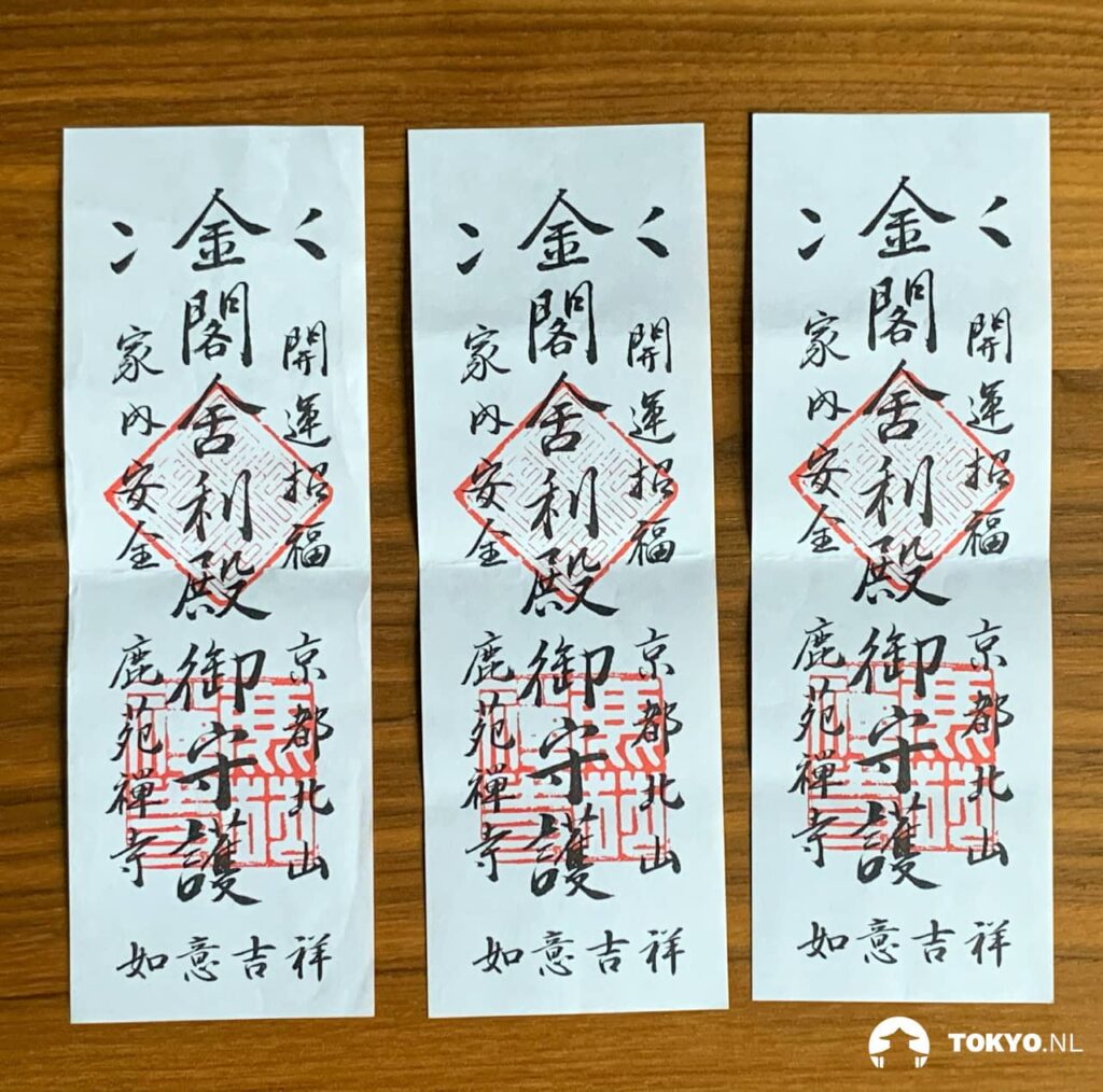 Three traditional Japanese temple stamps (goshuin) laid out on a wooden surface, featuring black calligraphy and red seals, which are ceremonial stamps collected by visitors at Buddhist temples and Shinto shrines