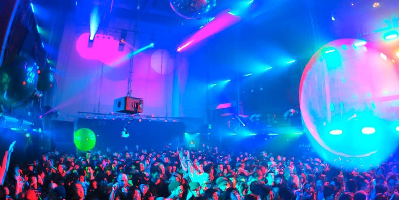 Spektakuläre Clubszene in Tokyo mit pulsierenden blauen und pinken Neonlichtern, einer großen Menschenmenge auf der Tanzfläche und futuristischen Lichteffekten an der Decke