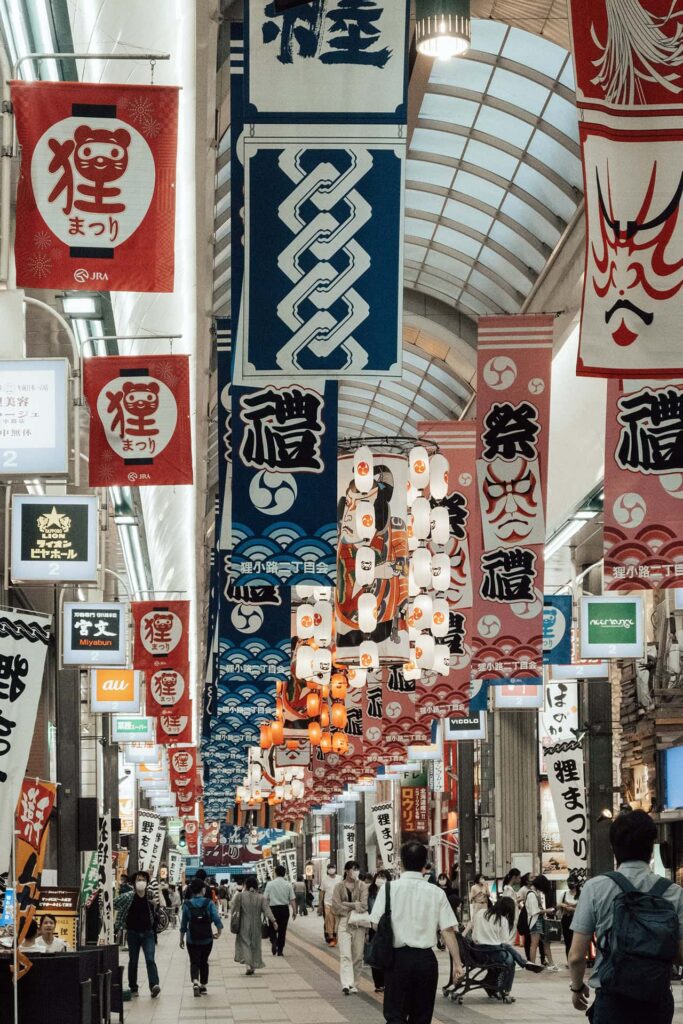 Lebendige Einkaufsstraße in Japan mit bunten Schildern, Laternen und Besuchern