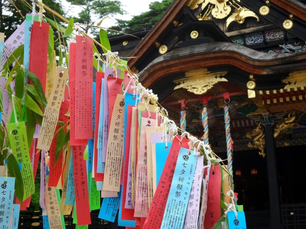 Bunte Tanzaku-Wunschzettel hängen an Bambuszweigen vor einem Shinto-Schrein während des Tanabata Festivals