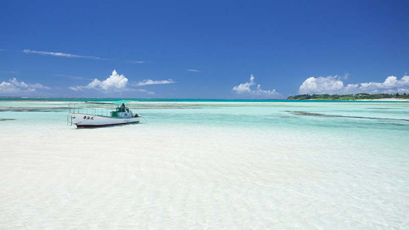 Kristallklares türkisfarbenes Wasser und weißer Sandstrand auf Amami-Oshima mit Boot