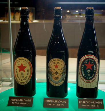 Drei historische japanische Bierflaschen in einem Museum oder einer Ausstellung
