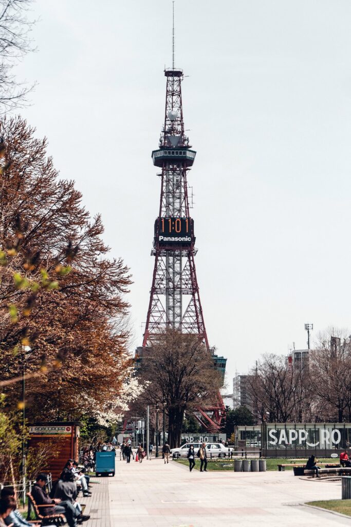 Sapporo TV Tower im Herbst umgeben von bunten Laubbäumen und Parkbesuchern