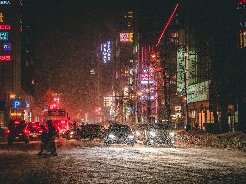 Nachts schneebedeckte Straße in Sapporo mit Neonlichtern und Verkehr