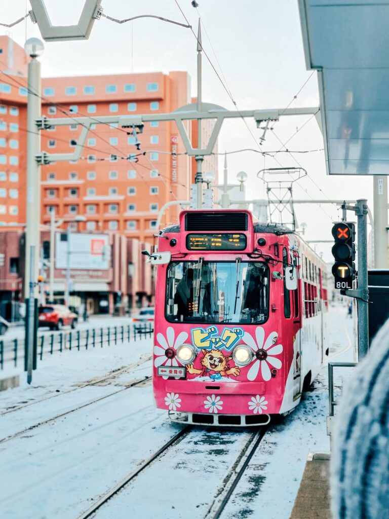 Rosa Straßenbahn in Sapporo mit Blumenmuster im Winter
